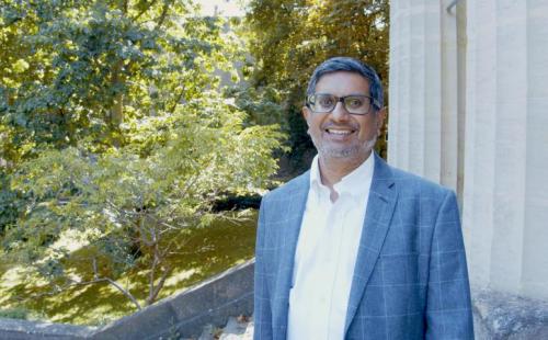 Samir Savant, CEO of St George's Bristol Samir Savant, CEO of St George's Bristol, standing outside on top of some stairs with some pillars and greenery in the background.