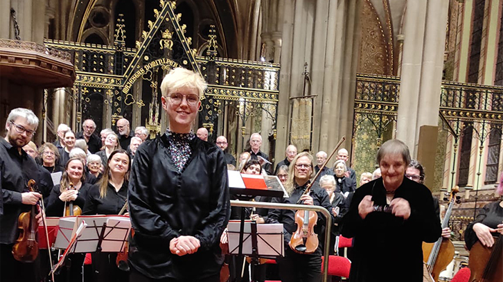 music creator poses with choir in church at the premiere