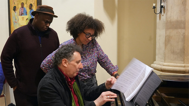 three musicians looking at a piano music sheet