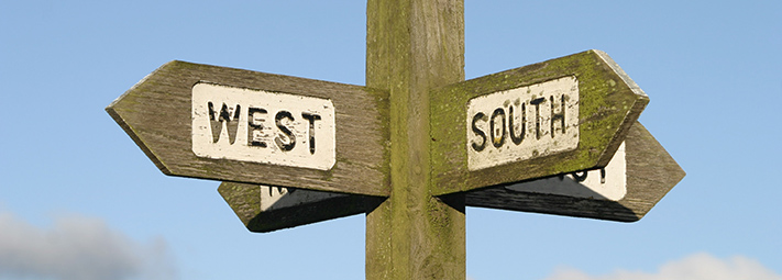 wooden signpost pointing south and west