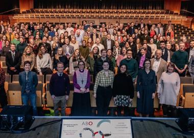 A group of delegates at the ABO conference standing in a theatre, picture taken from stage looking down. 