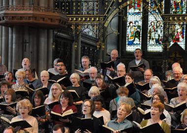 members of the choir singing, holding their scores, inside a church