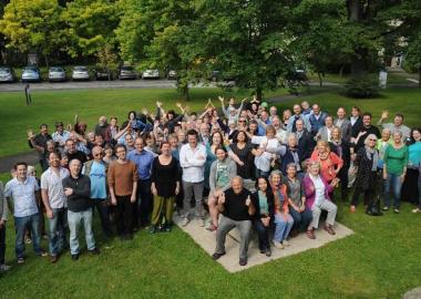 Photo showing a happy crowd of CoMA summer school attendees in front of a tree.