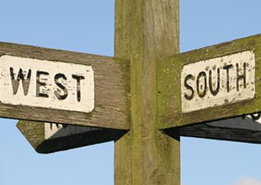 wooden signpost pointing south and west